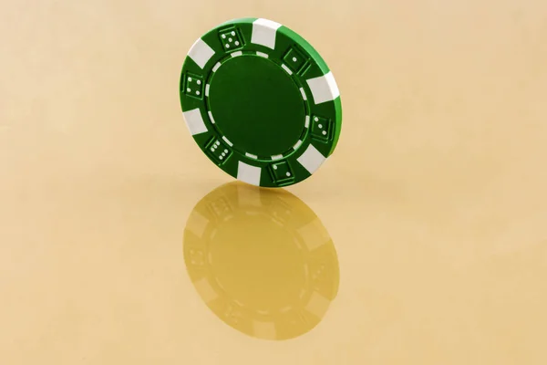 Groene casino chip is de moeite waard een rand op het reflecterende oppervlak — Stockfoto