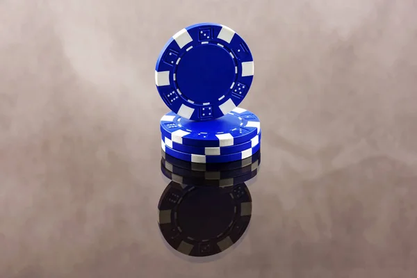 Blauwe casino chips worden doorgevoerd in een spiegelend oppervlak — Stockfoto