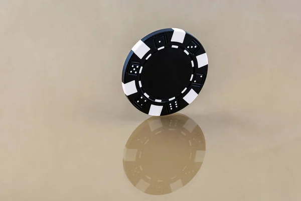 Een zwarte casino chip staat op het spiegeloppervlak — Stockfoto