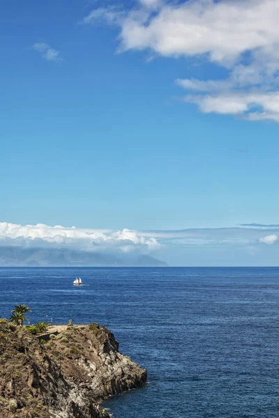 Seelandschaft. ein Segelboot mit weißen Segeln schwimmt an einem felsigen Ufer entlang — Stockfoto