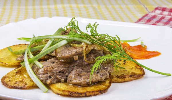 En rebanadas de papas fritas se encuentran trozos de carne frita — Foto de Stock