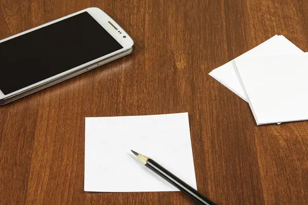 Bir akıllı telefon, notlar ve bir kalem masaya vardır