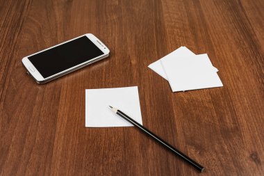 Bir akıllı telefon, bir kalem ve bir notlar sayfası bir tablo üzerinde yalan