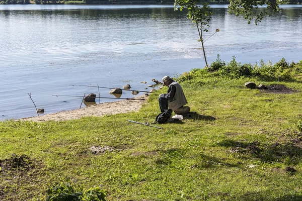 Göl kıyısında bir adam ile bir kaç balıkçılık çubuklar balıkçılık