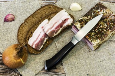 Sonraki bir tabloda iki siyah ekmek üzerinde tuzlanmış domuz eti dilim yalan 