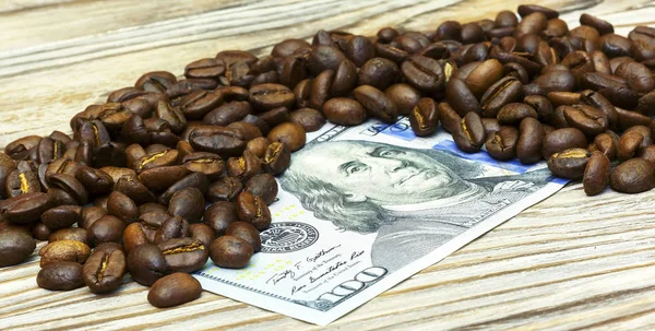 Korrels van koffie liggen op een geld-rekening, op een houten ondergrond — Stockfoto