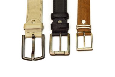 Three leather belts lie on a white background