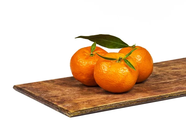 Tres mandarinas naranjas maduras sobre una superficie de madera — Foto de Stock