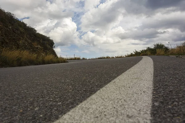 Camino de asfalto con un giro a la izquierda y un cielo nublado — Foto de Stock