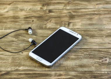 Akıllı telefon ve kulaklık yalan bir ahşap yüzeye yakın çekim