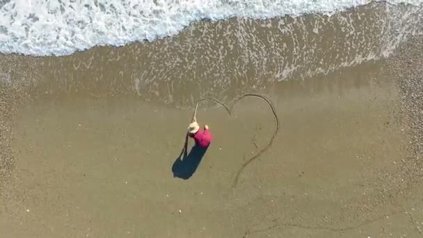 Young woman drawing heart on beach — Stock Video