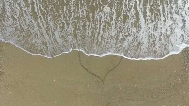 Jonge vrouw tekenen van hart op strand — Stockvideo