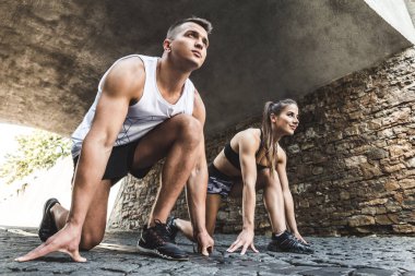 Eylem için hazır. Genç bir çift bir çalıştırmak için başlangıç olarak yan görünüm.