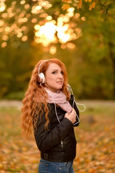 Kaunis nainen kuuntelee musiikkia kuulokkeilla — kuvapankkivalokuva