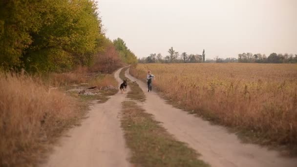 Vrolijke jongen loopt met een hond op de weg — Stockvideo