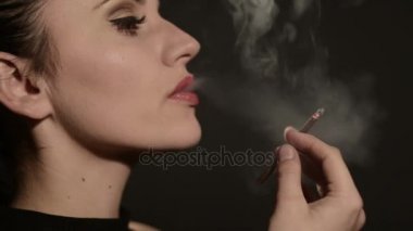 güzel kadın siyah bir arka plan üzerinde bir sigara içiyor