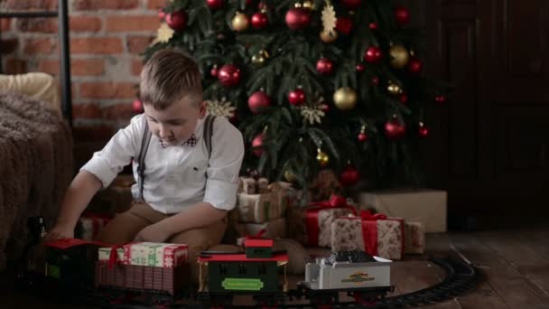 Niño jugando cerca del tren del árbol de Navidad — Vídeos de Stock