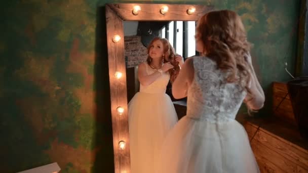 Молода красива жінка доглядає біля дзеркала з лампами — стокове відео