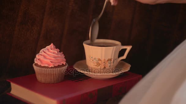 Frau trinkt Tee mit einem Cupcake, Nahaufnahme — Stockvideo