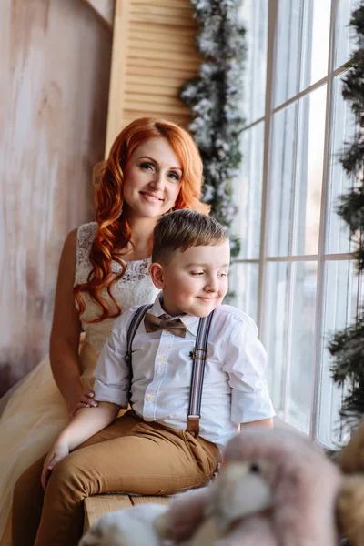 Mutter und Sohn sitzen am Fenster im Raum mit der Weihnachtsdekoration. — Stockfoto