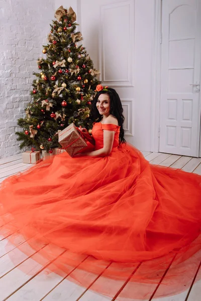 クリスマス ツリーの近くの豪華な赤いドレスで美しい女性 — ストック写真