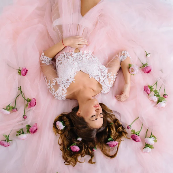 Γυναίκα σε μια ροζ σάλτσα φόρεμα ξαπλωμένη στο κρεβάτι — Φωτογραφία Αρχείου