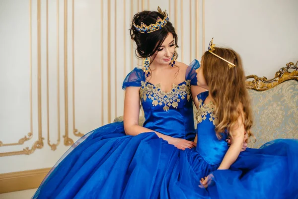 Beautiful princess mother and daughter in a gold crown