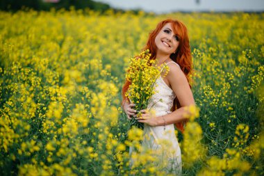Kolza tohumu alanında genç Kızıl saçlı kadın
