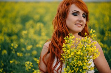 Kolza tohumu alanında genç Kızıl saçlı kadın