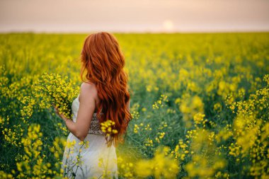 Kolza tohumu alanında genç Kızıl saçlı kadın