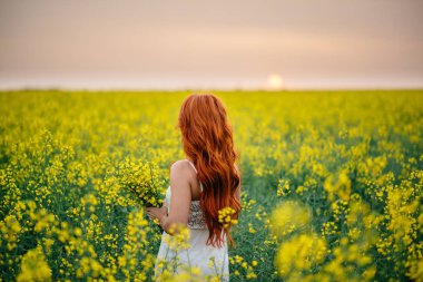 Kolza tohumu alanında genç Kızıl saçlı kadın