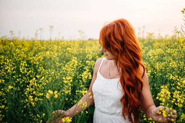 Jovem ruiva em um campo de colza — Fotografia de Stock