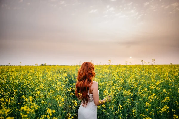 年轻的红头发女人在油菜田 — 图库照片