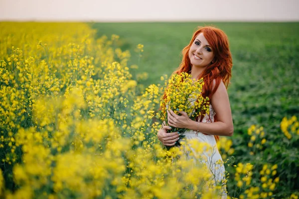 Jovem ruiva em um campo de colza — Fotografia de Stock