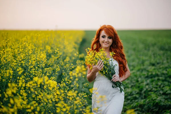 Jovem ruiva em um campo de colza — Fotografia de Stock