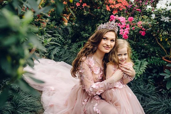 Mãe e filha em luxuosos vestidos de cor de pêssego em um jardim florido — Fotografia de Stock