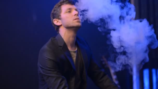 Młody człowiek vaping z elektroniczny papieros i zrobić trochę dymu chmury — Wideo stockowe