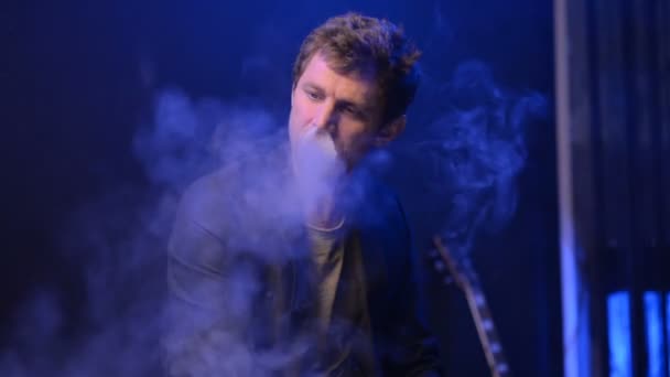 Jovem vaping com um cigarro eletrônico e fazer algumas nuvens de fumaça — Vídeo de Stock