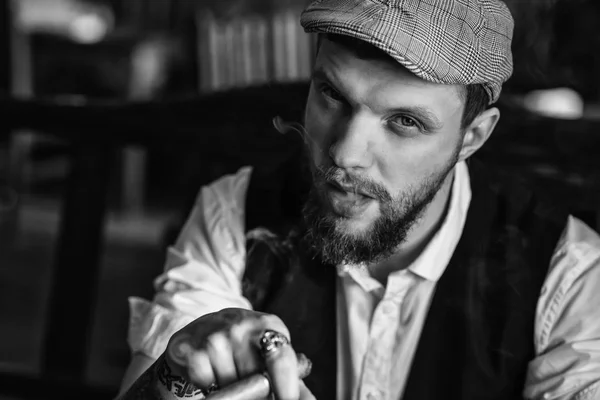 A young bearded man smoking a cigar in a pub — Stock Photo, Image