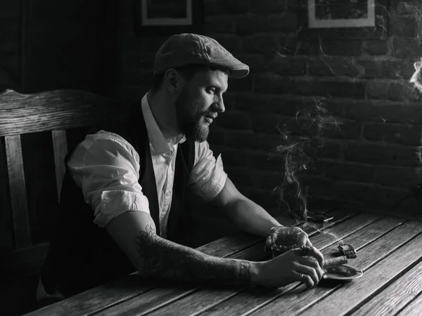 A young bearded man smoking a cigar in a pub — Stock Photo, Image