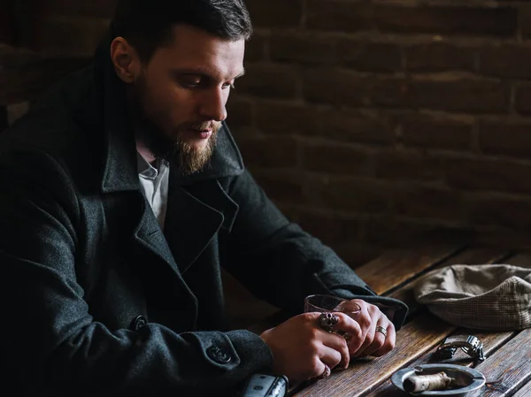 Young bearded man drinks whiskey in a pub, vintage style — Stock Photo, Image