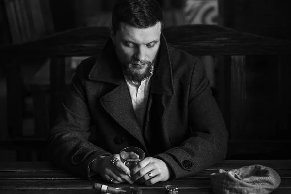 Young bearded man drinks whiskey in a pub, vintage style — Stock Photo, Image