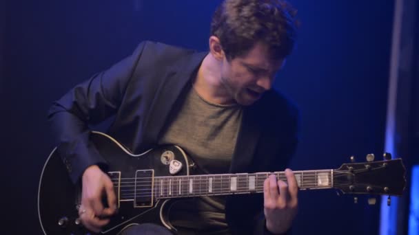 Ένας άντρας παίζει μια ηλεκτρική κιθάρα και τραγουδά σε ένα σκοτεινό δωμάτιο — Αρχείο Βίντεο