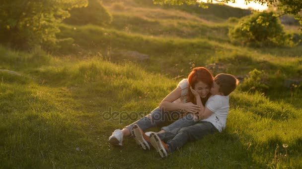 Mother and son having fun outdoors sitting on grass — Stock Video