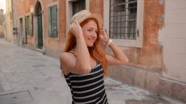 genç kadın elini kolunu sallaya antik bir Avrupa kenti sokaklarında dönüyor