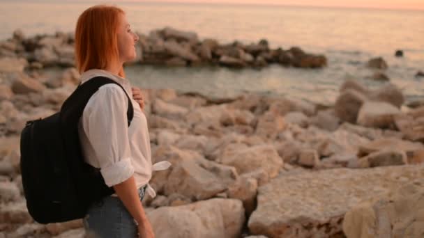 Νεαρή γυναίκα τουριστικές περπατώντας σε ένα βραχώδης θαλάσσια ακτή — Αρχείο Βίντεο