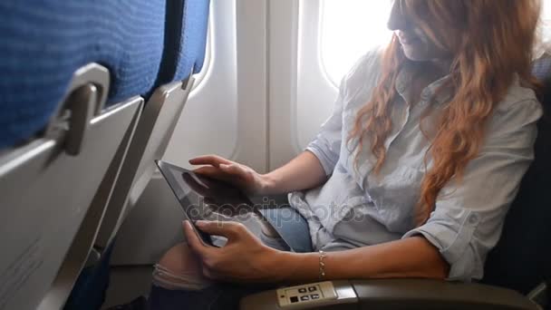 Vrouw met behulp van een tablet op een vliegtuig — Stockvideo