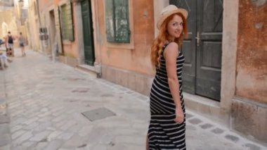 genç kadın elini kolunu sallaya antik bir Avrupa kenti sokaklarında dönüyor