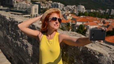gözlük ve şapka genç kadın selfie bir antik kent arka plan üzerinde yapar.