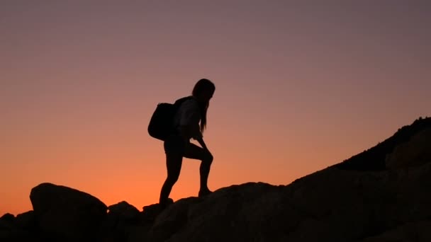 Silhouette of a female tourist who climbs a mountain — Stock Video